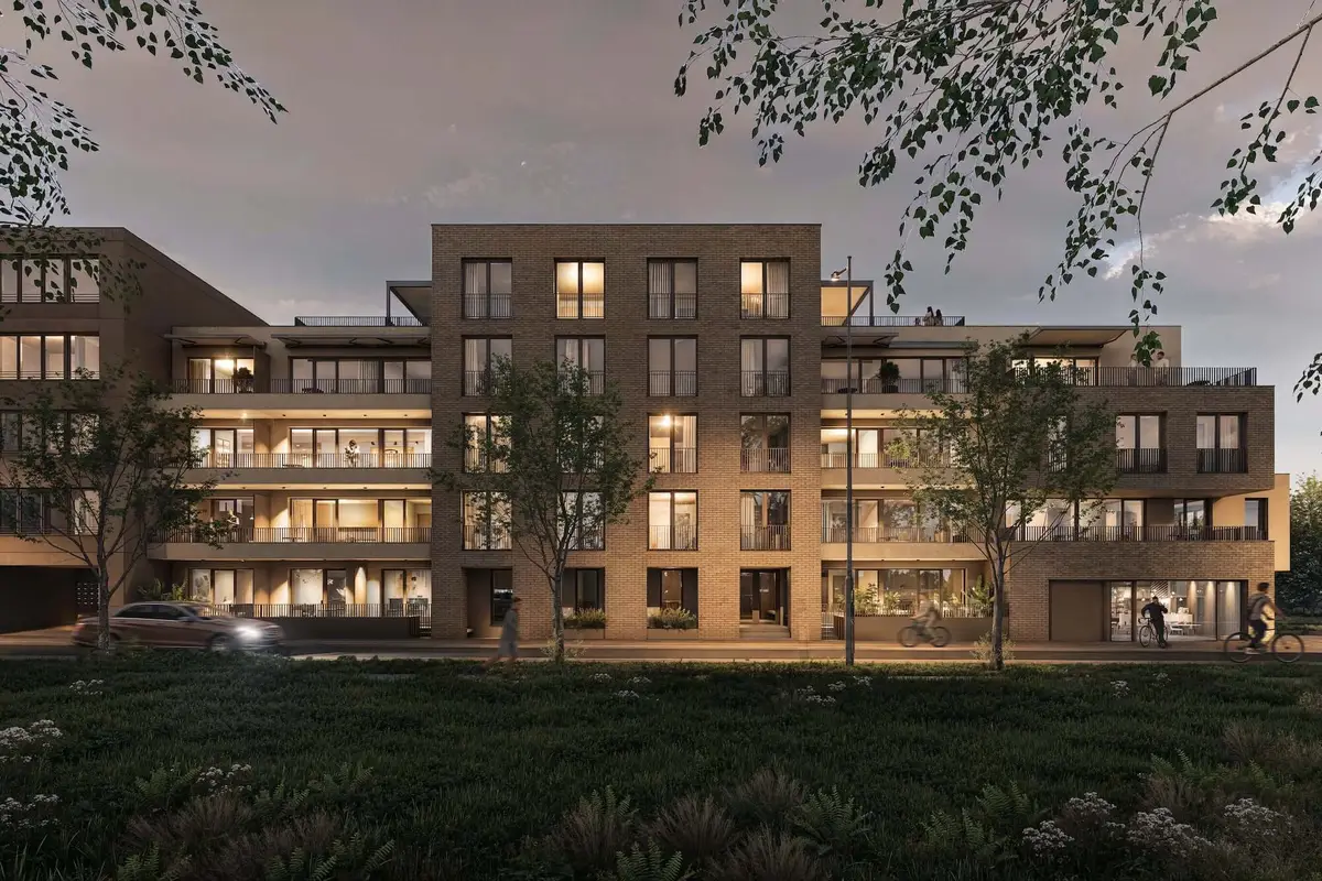 Vizualizace bytového domu projektu Porta Hradec – cihlová fasáda s balkony, ve večerním osvětlení, kolem zeleň a stromy